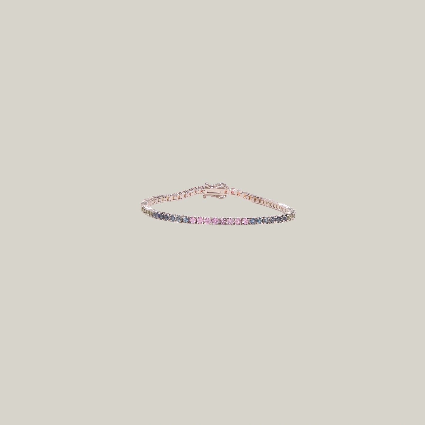 A blue and pink sapphire tennis bracelet on a light gray background