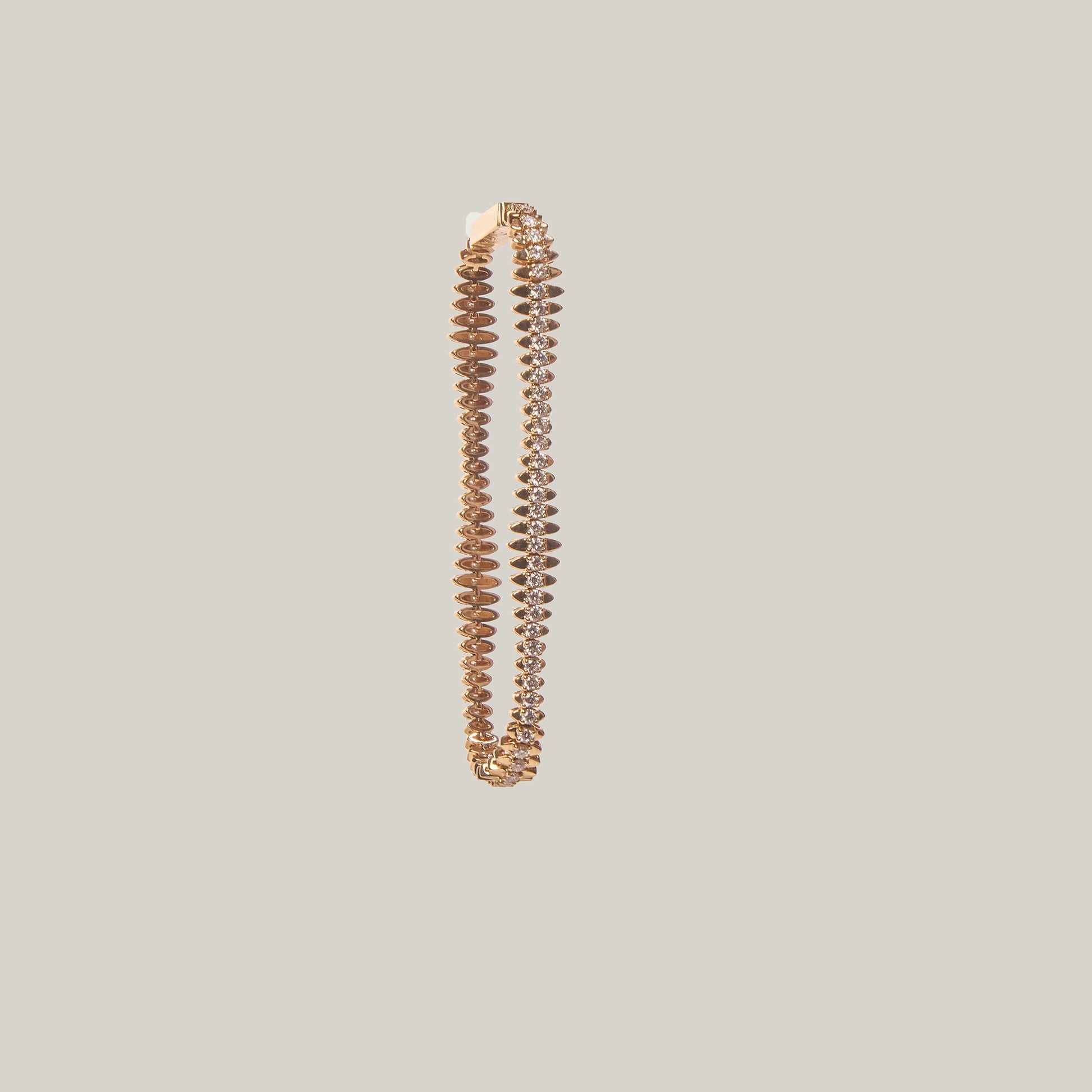 Gold tennis bracelet with diamonds shown on a light gray background
