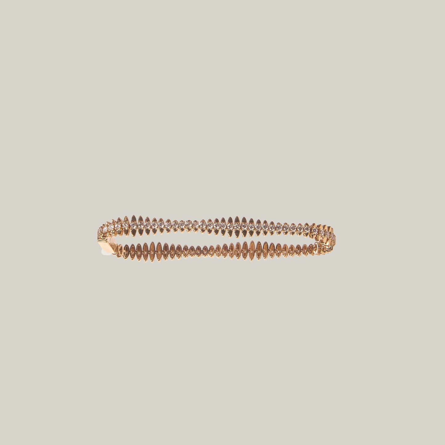 Close up of a gold bracelet with diamonds on a light gray background