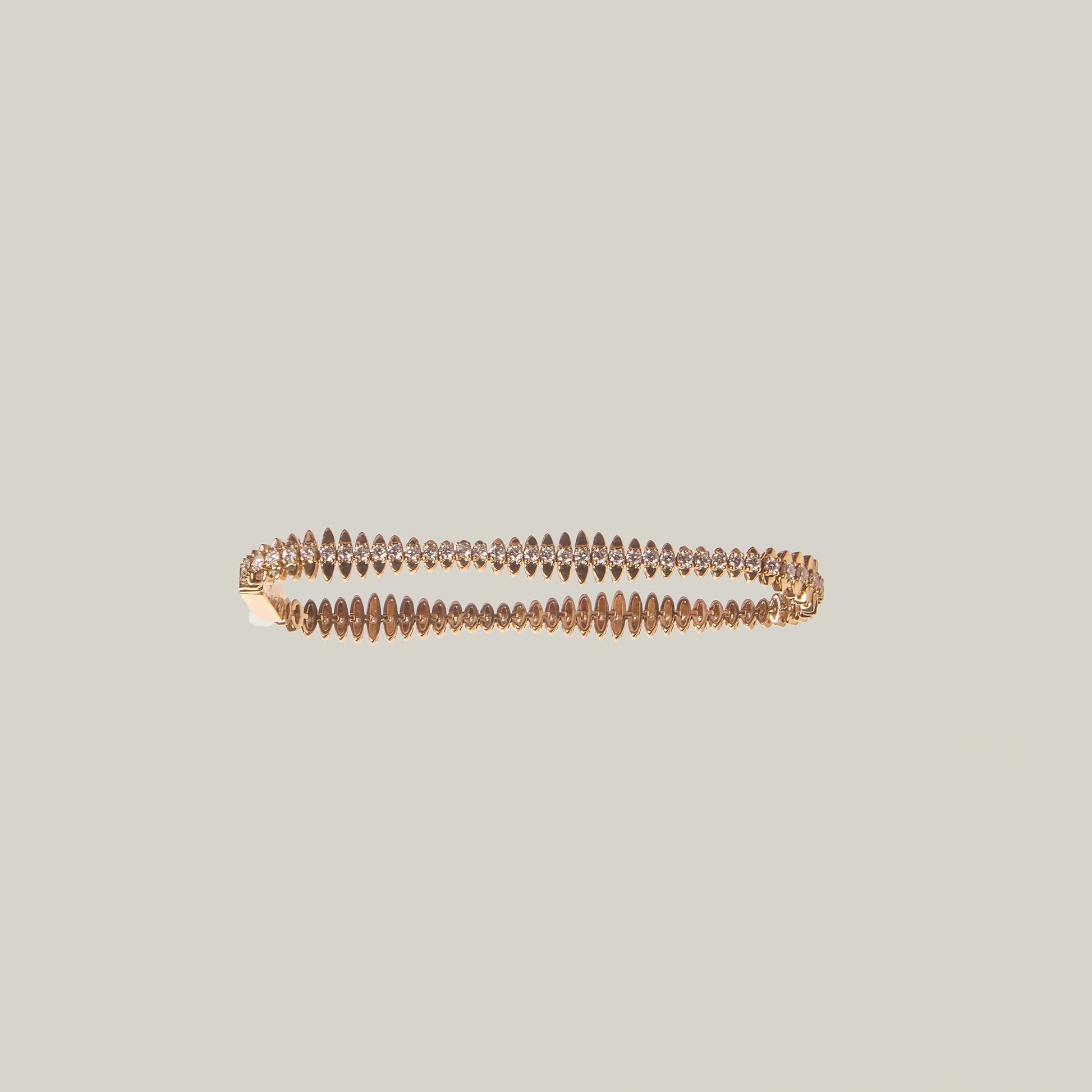 Close up of a gold bracelet with diamonds on a light gray background