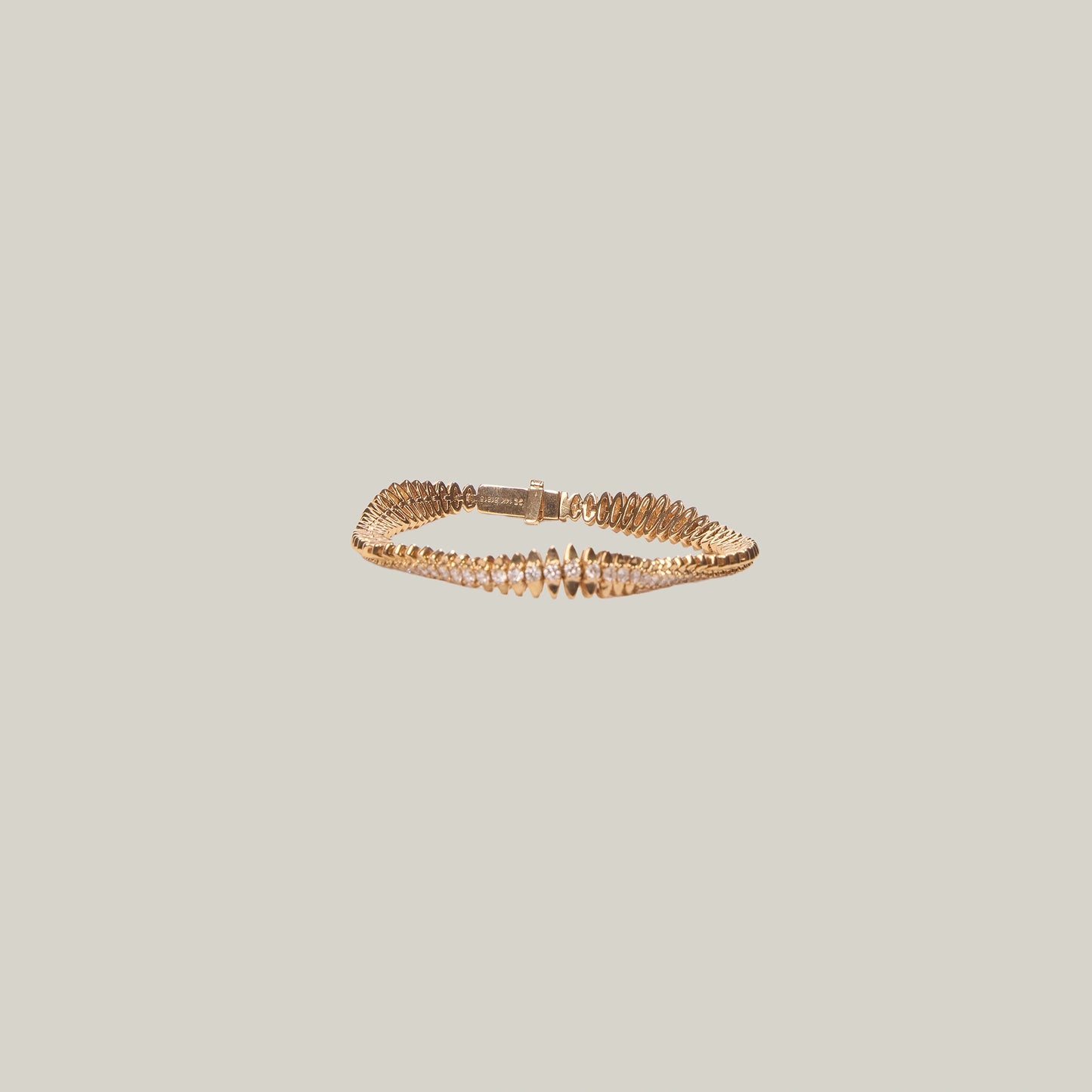 Gold tennis bracelet on a light gray background
