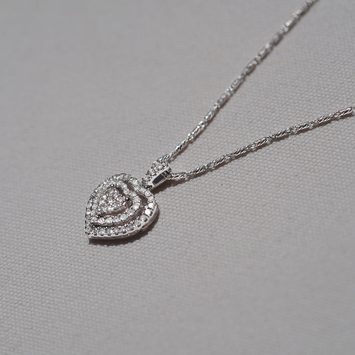 A 14k white gold diamond necklace with a cluster of shimmering stones against a neutral textured background.