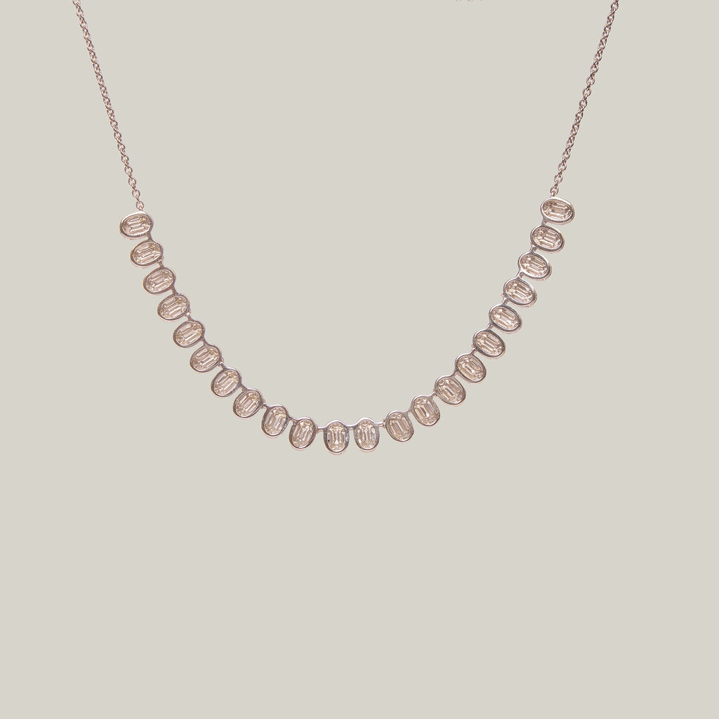 Rear view of a gold necklace with diamonds in a curved pattern on a light gray background