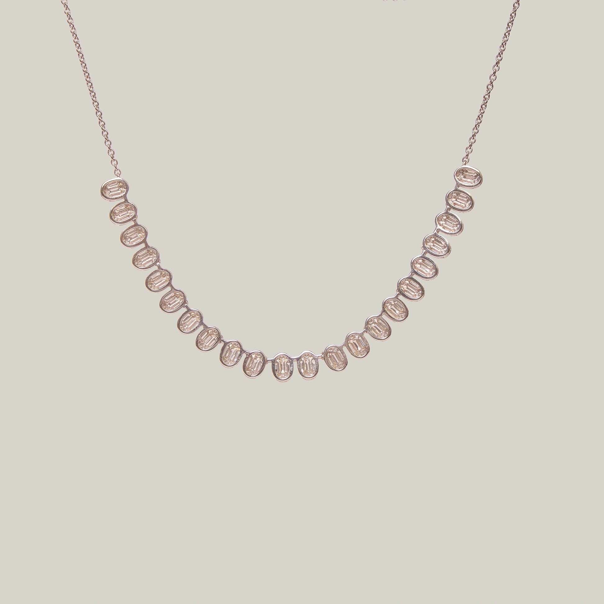 Rear view of a gold necklace with diamonds in a curved pattern on a light gray background