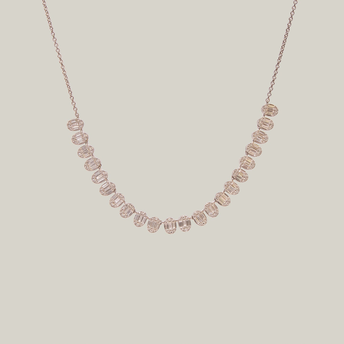 Gold necklace with diamonds in a curved pattern on a light gray background