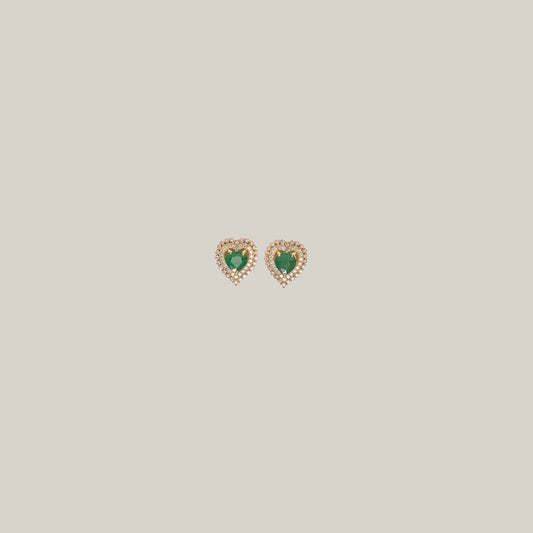 Pair of heart-shaped emerald earrings with a diamond border on a light gray background