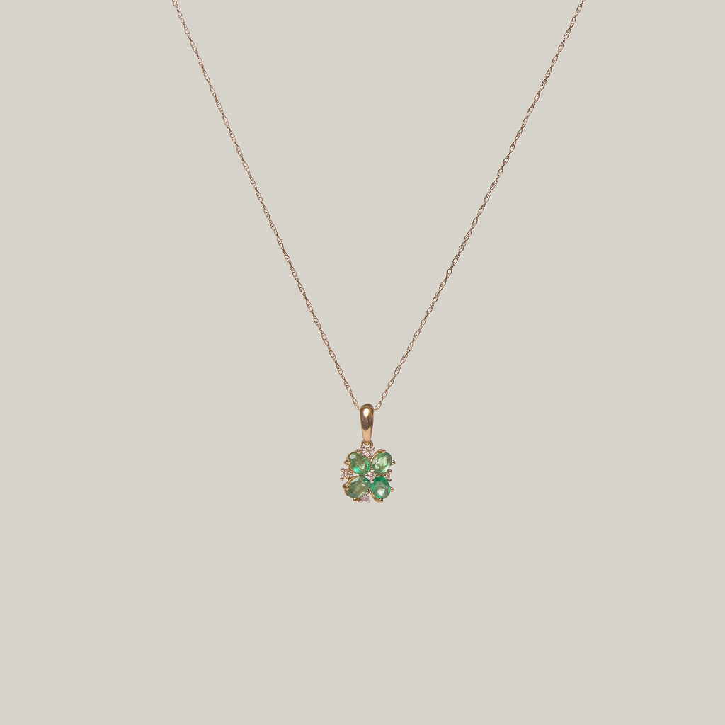 Close-up front-facing view of a green four leaf clover pendant on a light gray background