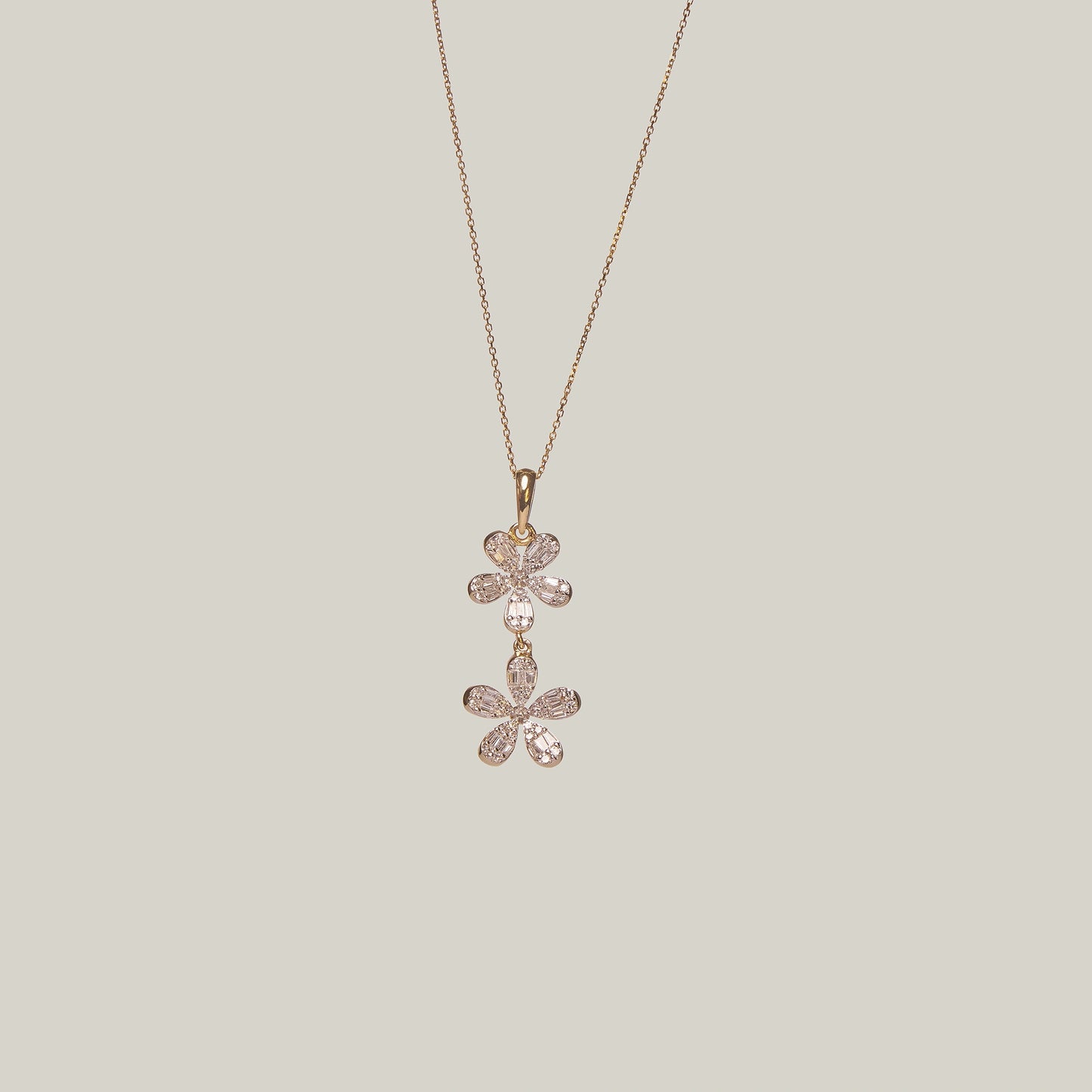 Close-up front-facing view of a gold double flower diamond necklace on a light gray background