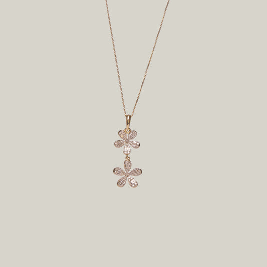 Close-up front-facing view of a gold double flower diamond necklace on a light gray background