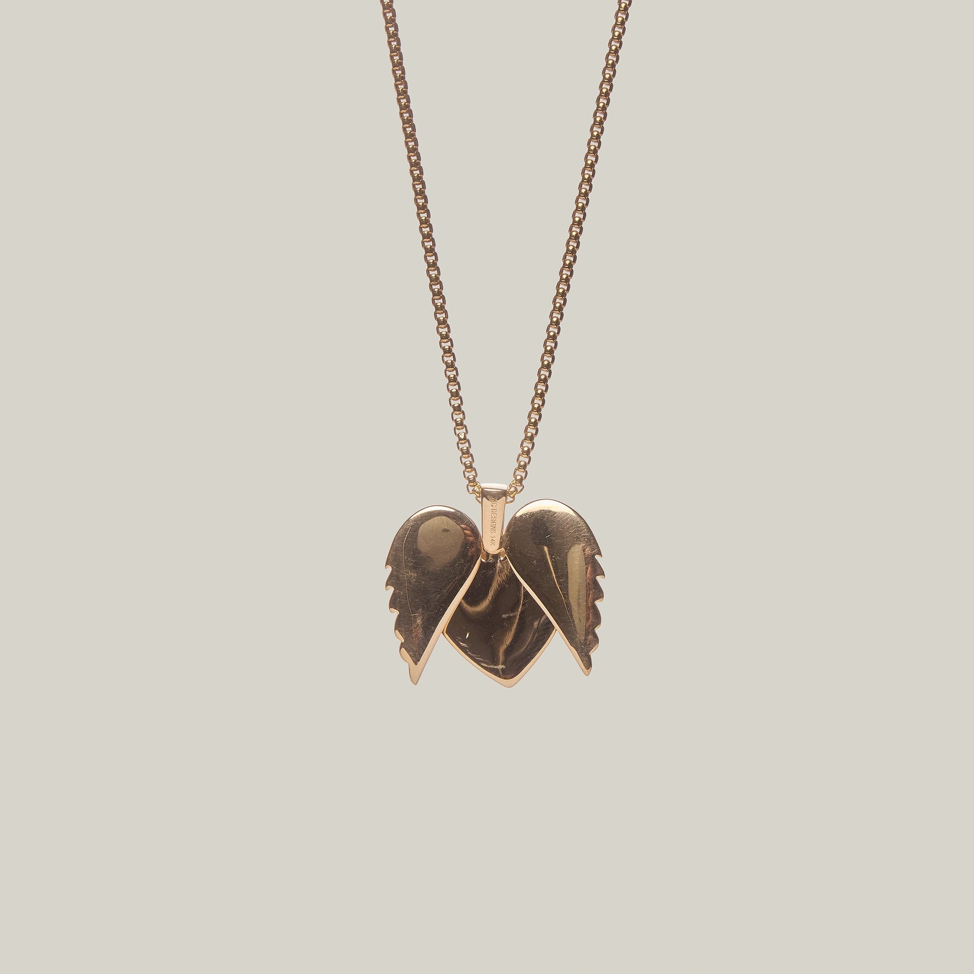 Close-up rear-facing view of a gold heart pendant with an opened angel wings design, encrusted with diamonds, on a light gray background