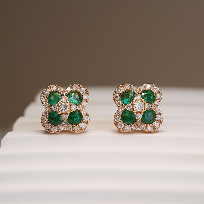 A pair of emerald royal earrings with a geometric pattern, set in gold, displayed on a flat surface.