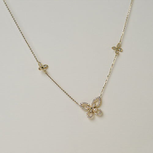 A gold-colored necklace featuring three butterfly-shaped charms with intricate detailing, displayed on a neutral background.
