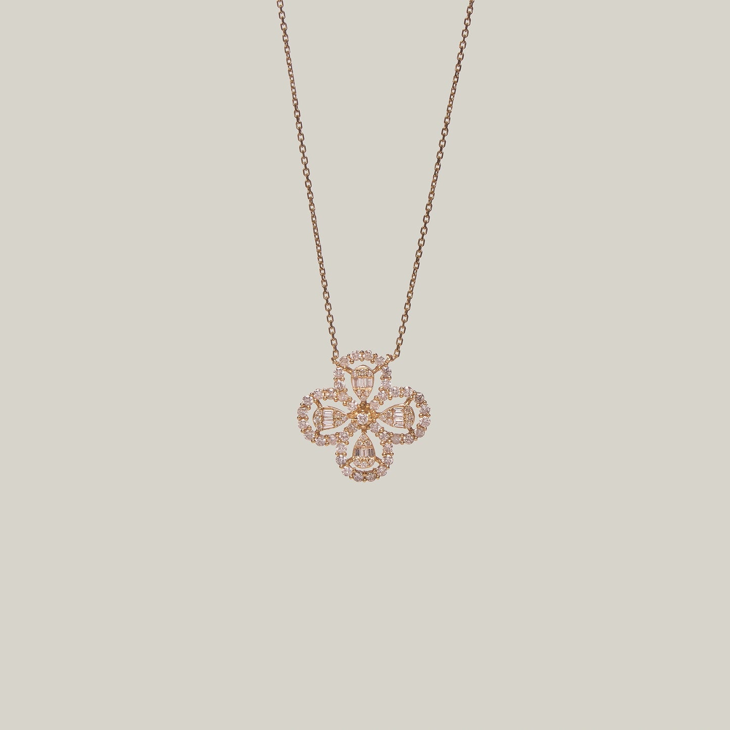Close-up front-facing view of a rose gold necklace with a four leaf clover pendant encrusted with diamonds on a light gray background.