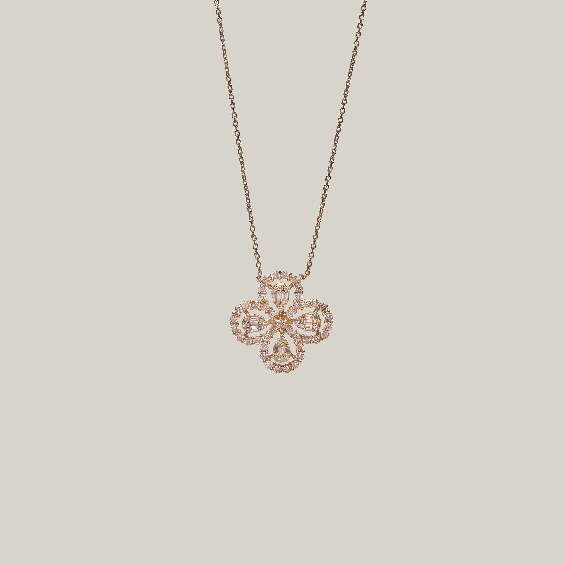 Close-up front-facing view of a rose gold necklace with a four leaf clover pendant encrusted with diamonds on a light gray background.