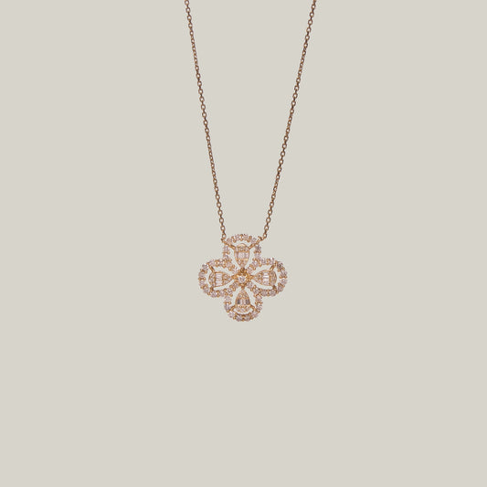 Close-up front-facing view of a rose gold necklace with a four leaf clover pendant encrusted with diamonds on a light gray background.