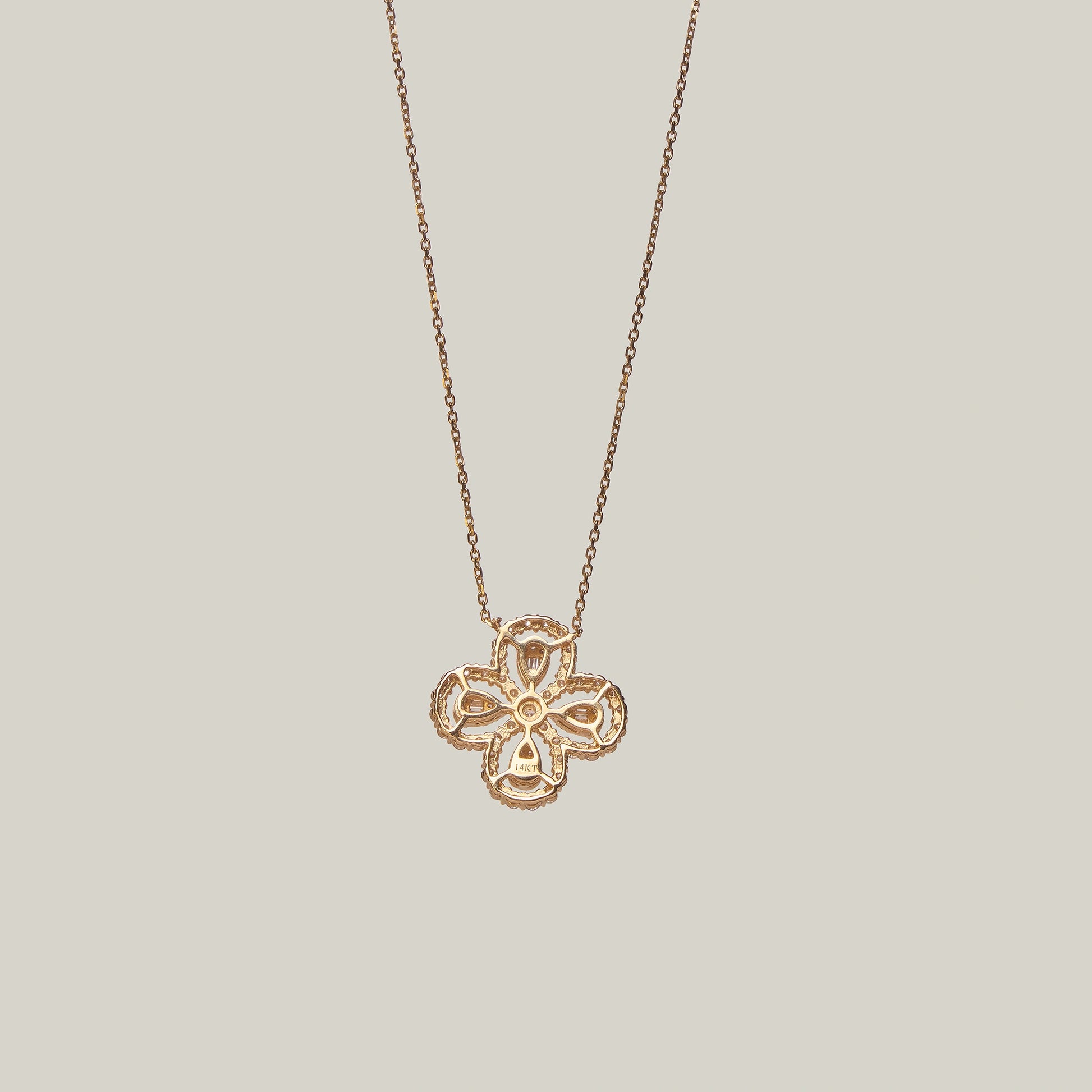 Close-up rear-facing view of a rose gold necklace with a four leaf clover pendant encrusted with diamonds on a light gray background.