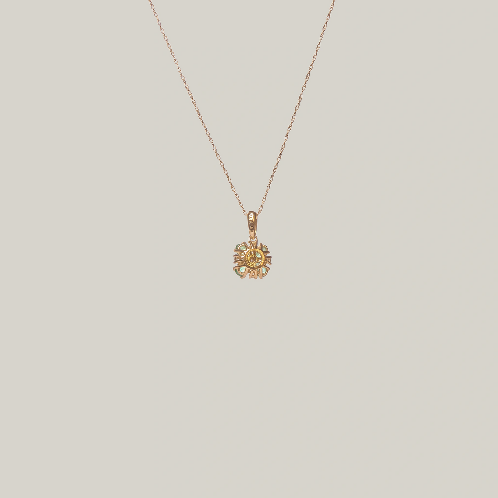 Close-up rear-facing view of a green four leaf clover pendant on a light gray background