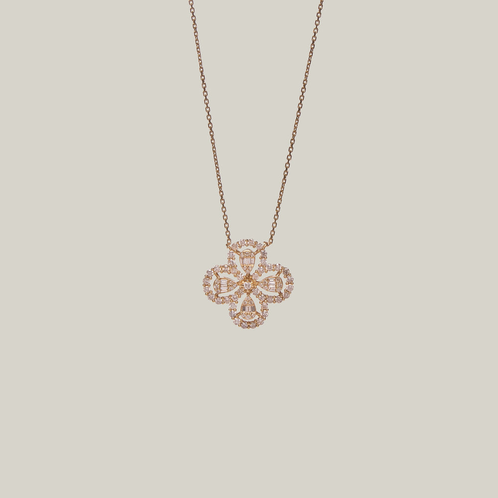 Close-up front-facing view of a four leaf clover pendant encrusted with diamonds on a light gray background.