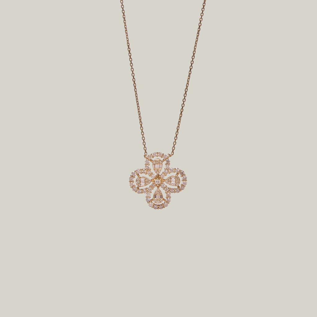 Close-up front-facing view of a four leaf clover pendant encrusted with diamonds on a light gray background.