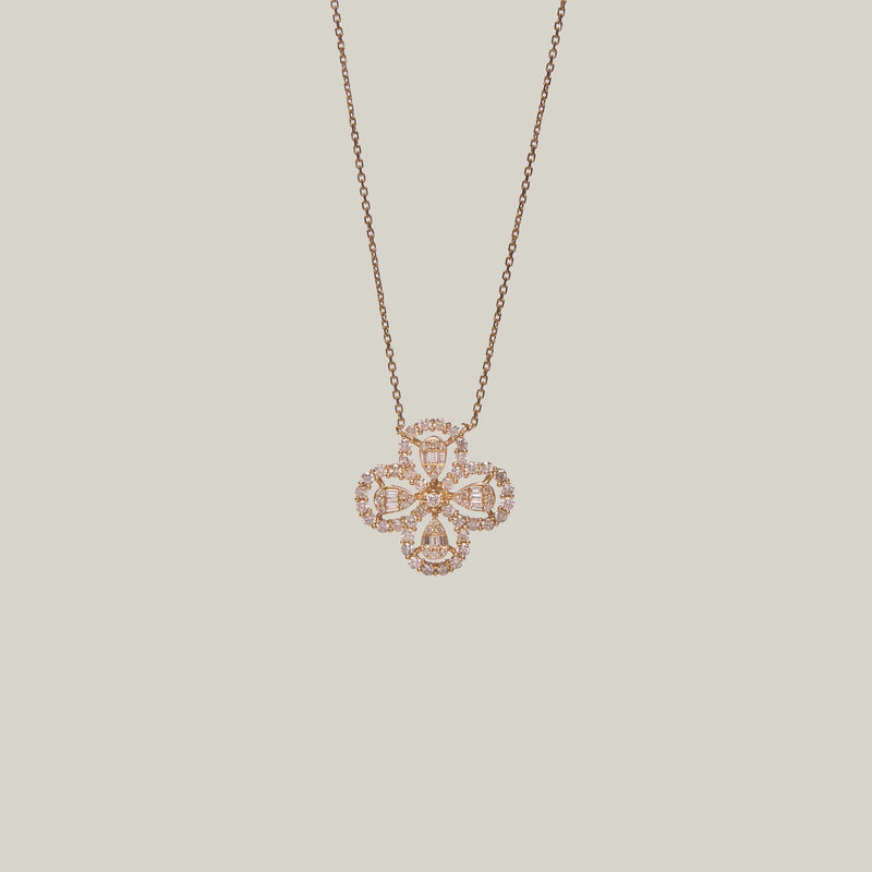 Close-up front-facing view of a four leaf clover pendant encrusted with diamonds on a light gray background.
