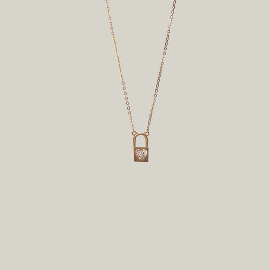 Close-up front-facing view of a gold and diamond padlock necklace on a light gray background