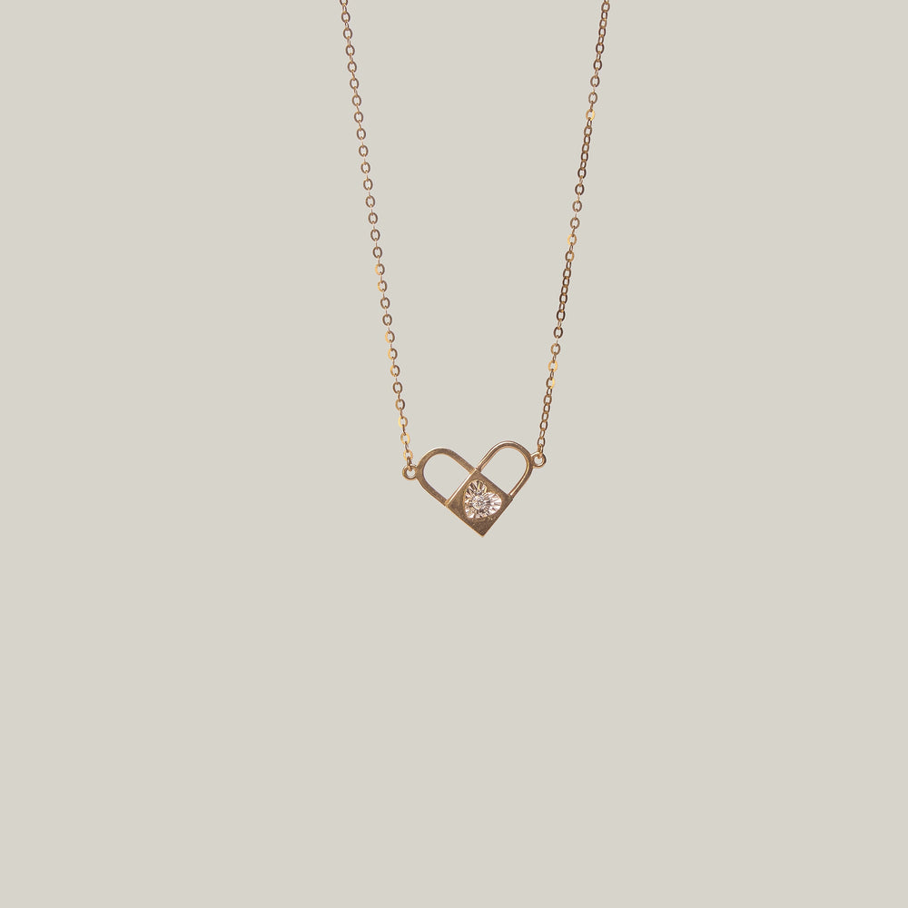Close-up front-facing view of an opened gold and diamond padlock pendant with heart shape on a light gray background