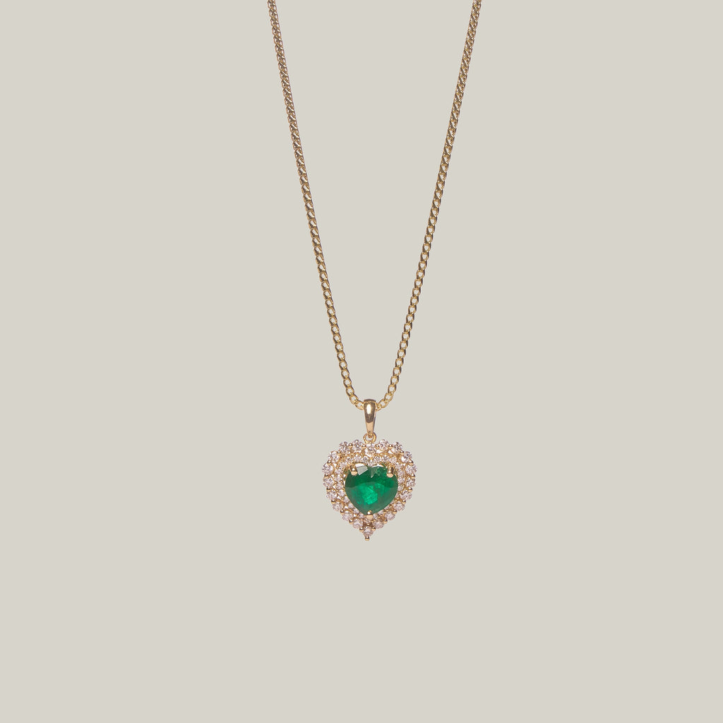 Front-facing close-up of a heart-shaped emerald pendant on a light gray background