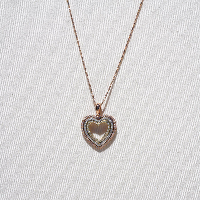 A gold diamond heart necklace suspended from a chain against a white textured background.