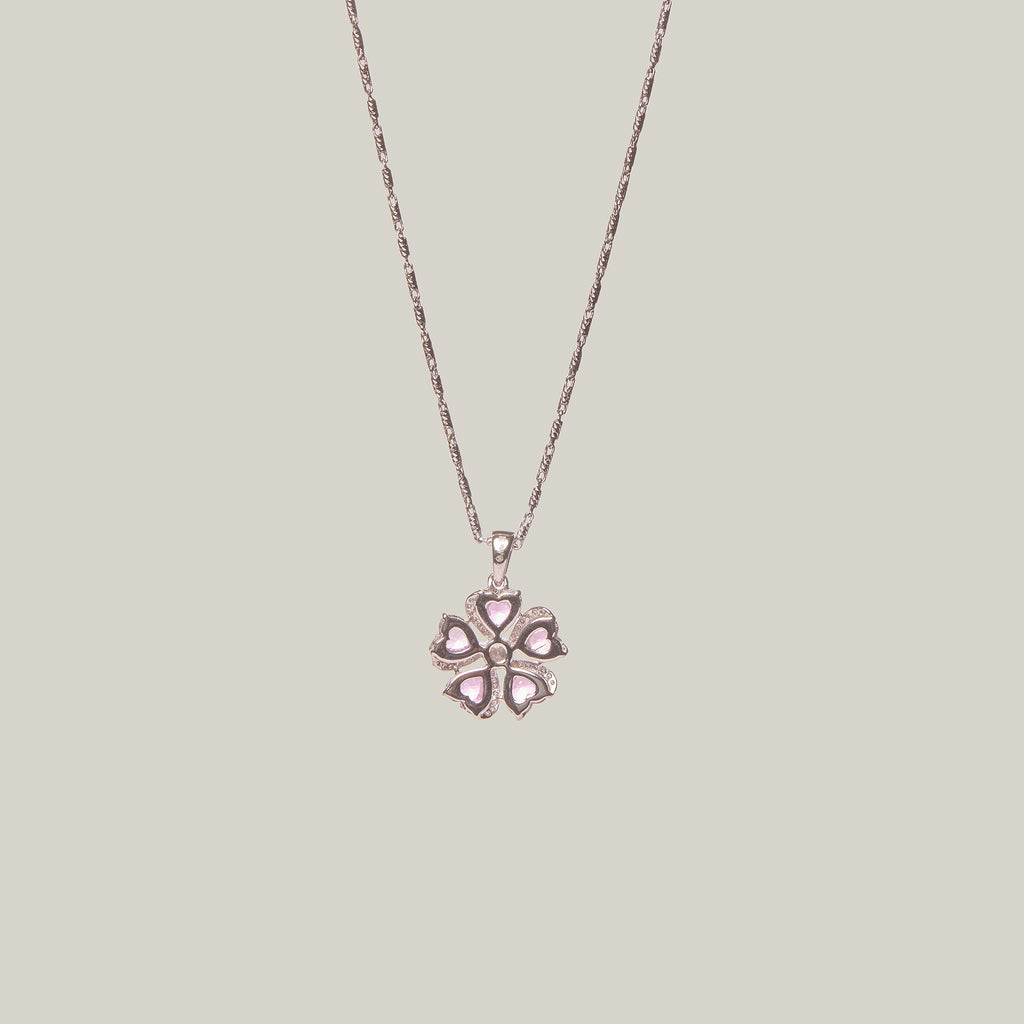 Reverse view of a necklace with a pink flower-shaped pendant on a light gray background