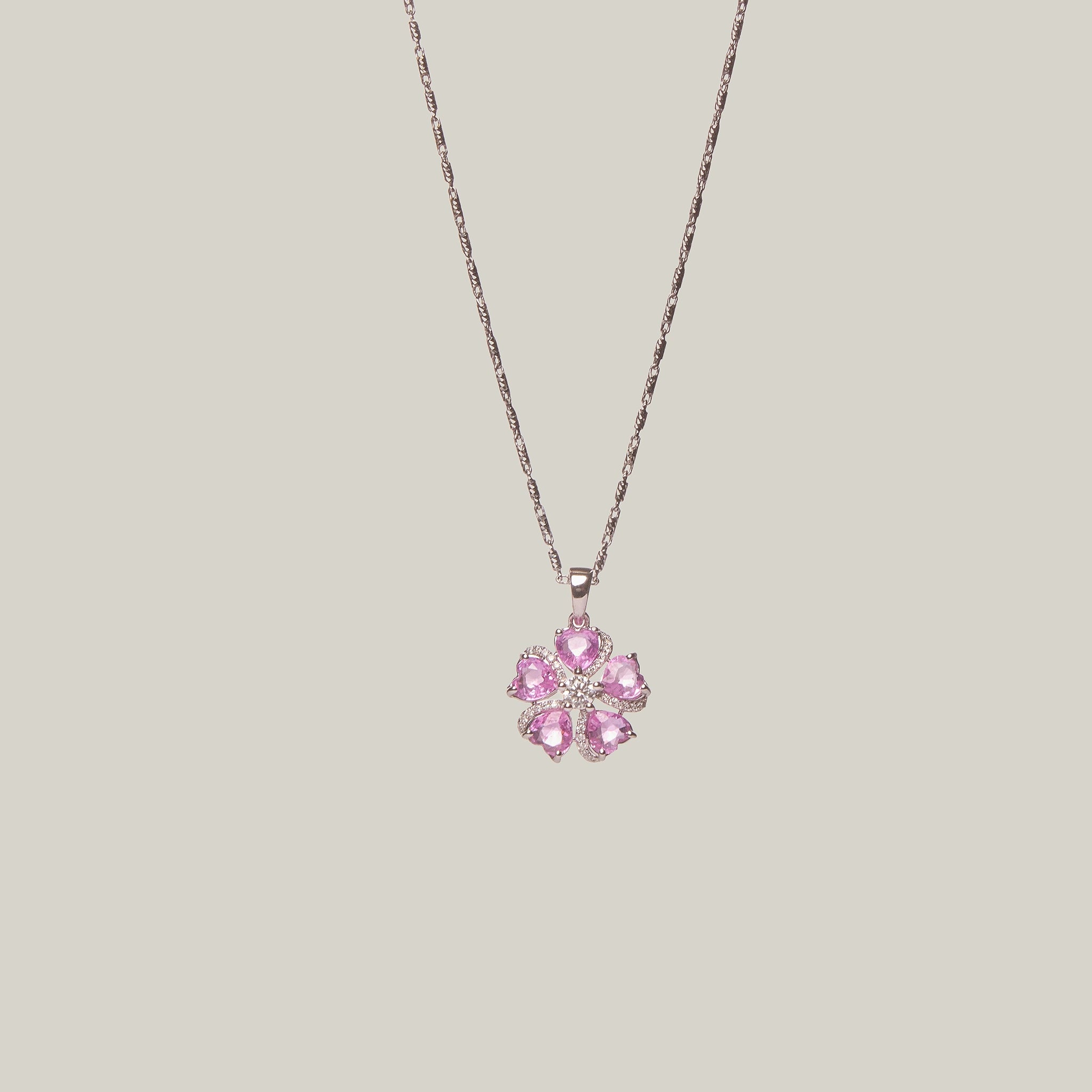Necklace with a pink flower-shaped pendant on a light gray background