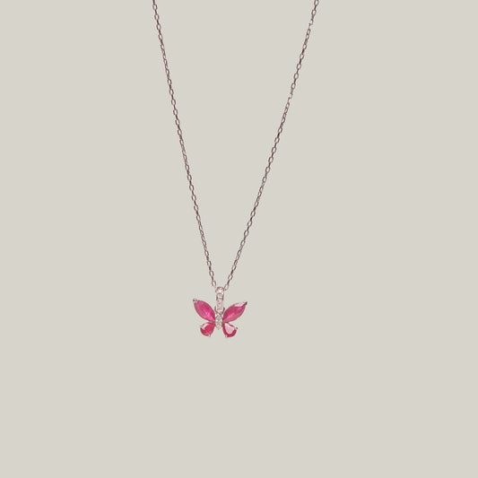 Butterfly-shaped pink pendant on a chain against a light gray background