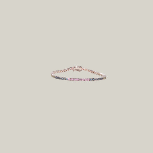 A blue and pink sapphire tennis bracelet on a light gray background