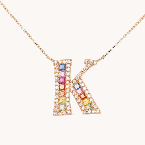 A necklace in the letter K with encrusted diamonds outlining the shape and multicolored sapphires in the center.